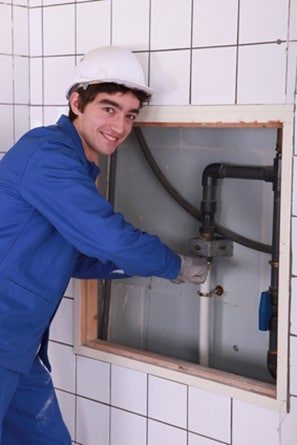 Young plumber working in bathroom