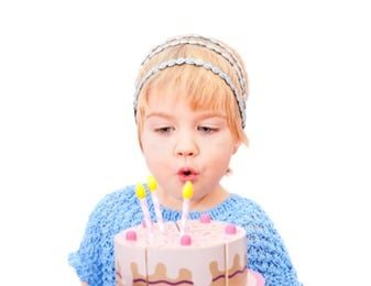 Pretty little girl blowing on candles in the cake