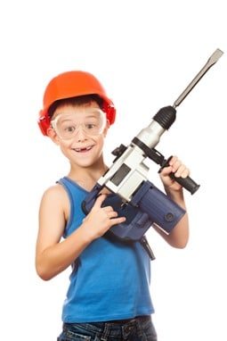 little boy in a helmet with electric hammer